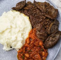 a blue plate topped with meat, mashed potatoes and beans