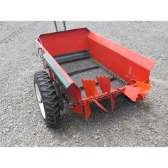 a red tractor trailer sitting on top of gravel