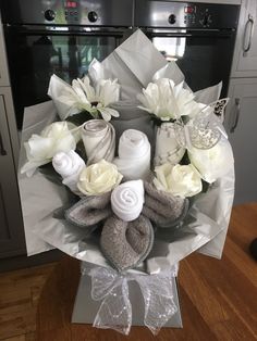 a bouquet of white flowers and baby items in a wrapper on top of a table