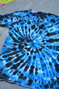 a blue and black tie - dyed t - shirt laying on the ground next to flowers