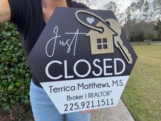 a woman holding up a sign that says just closed with a house and key on it