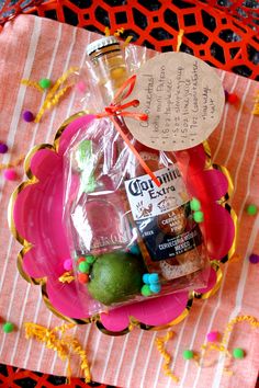 a bottle of alcohol sitting on top of a pink plate covered in confetti