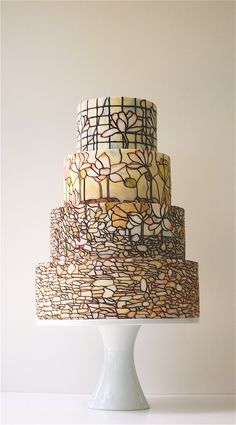 a three tiered cake on top of a white pedestal with decorative frosting and designs