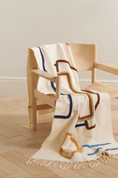 a chair with a blanket on top of it next to a white wall and wooden floor