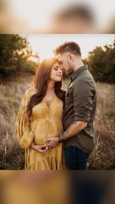 a pregnant couple standing in the grass at sunset