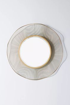 a white and gold plate with a circular mirror on the wall in front of it