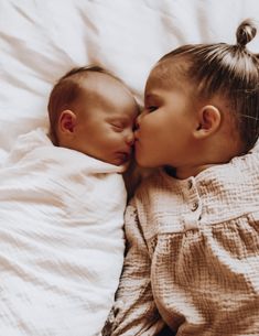 two babies are laying down and kissing each other