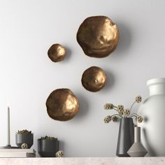 three gold plates are hanging on the wall next to vases and other decor items