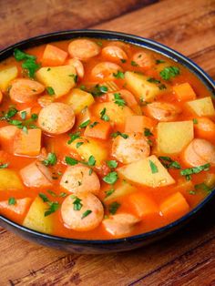 a bowl filled with shrimp and carrots on top of a wooden table