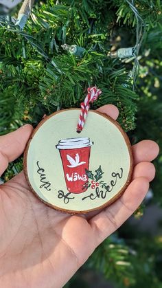 a hand holding a christmas ornament with a cup on it