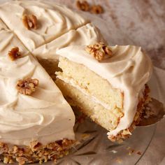 a cake with white frosting and walnuts on top is cut in half to show the inside