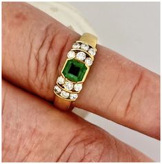 a close up of a person's hand with a ring on their finger and an emerald in the middle