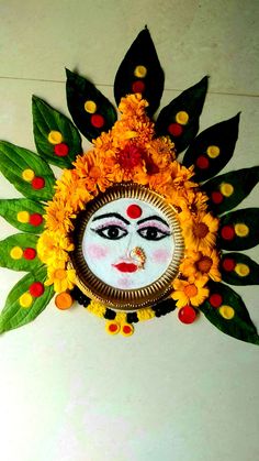 a decorative wall hanging with leaves and flowers on it's face in the center