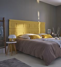 a bedroom with yellow headboard and grey walls