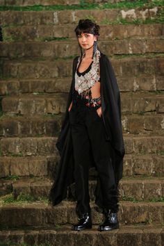 a woman standing on some steps wearing black pants and a shawl over her head