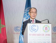 a man standing at a podium in front of flags