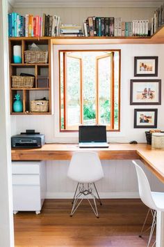 a laptop computer sitting on top of a desk next to a window with bookshelves