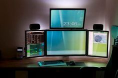 three computer monitors sitting on top of a wooden desk