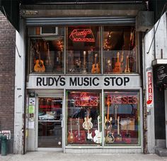 a music store with guitars and other musical instruments in the front window that says rudy's music stop