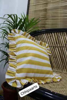 a pillow sitting on top of a wicker chair next to a potted plant