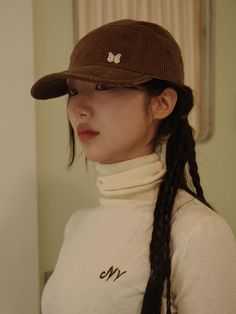 a woman wearing a brown hat with braids in her hair and a white turtle neck sweater