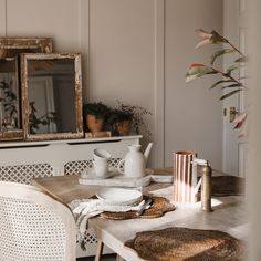 a dining room table with plates, cups and vases sitting on top of it