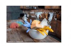 a wooden table topped with a white bowl filled with cleaning supplies