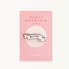 a pink party mountain pin sitting on top of a white card with a ribbon around it