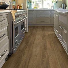 a kitchen with wood flooring and white cabinets in the middle of it is shown