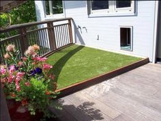 a flower pot with flowers in it sitting on a wooden deck next to a house