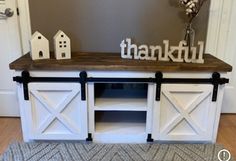 a white entertainment center with sliding doors and a sign that says thank you on it