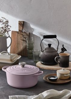 a table topped with pots and pans filled with food next to a tea kettle