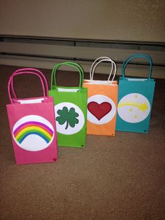 four bags with different designs on them sitting in front of a door, one has a heart and the other has a rainbow