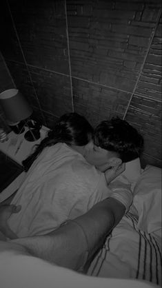 black and white photograph of two people laying in bed with their heads on each other