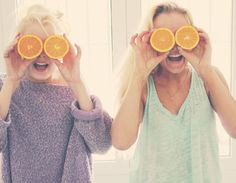 two women holding orange slices in front of their eyes