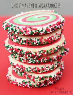 a stack of white and red cookies with sprinkles on top sitting on a red surface