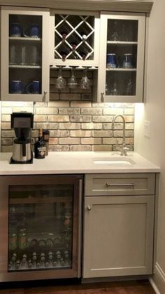 a small kitchen with white cabinets and grey counter tops, wine glasses on the shelves