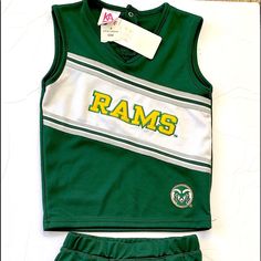 a green and white uniform with ram's on the front is laying on a table