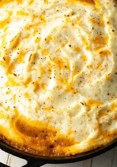 a baked dish with cheese and seasoning in a skillet on a wooden table