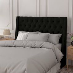 a black headboard with white sheets and pillows on a bed in a bedroom next to a night stand