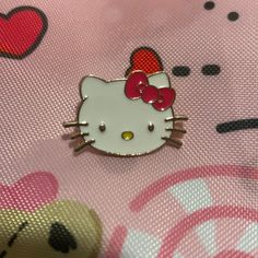 a hello kitty pin sitting on top of a pink fabric