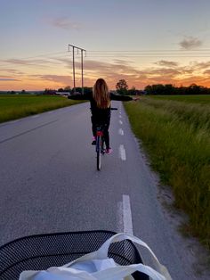 a woman riding her bike down the middle of a road at sunset or dawn with long hair blowing in the wind