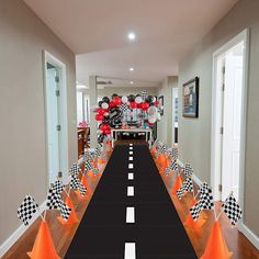 a long table is decorated with black and white checkered flags, orange cones, and red balloons