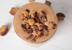 a glass filled with chocolate and nuts on top of a white table next to pieces of candy