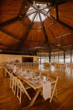 a large room with wooden floors and tables set up for a formal function in the center