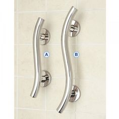 two chrome handles on a white tiled wall with blue letters in the upper right corner