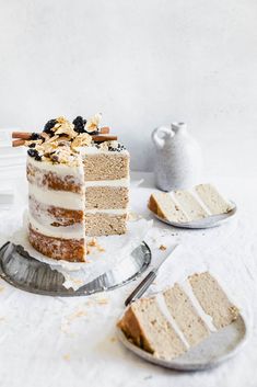 a slice of cake with white frosting on a plate next to another piece of cake