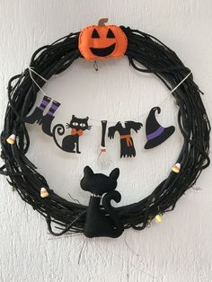 a wreath with halloween decorations hanging from it's side and a black cat on the front