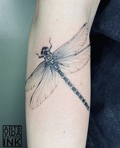 a small dragonfly tattoo on the arm