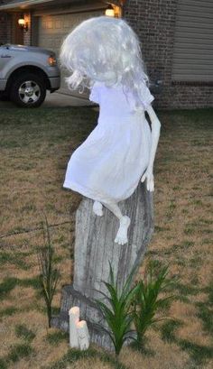 there is a statue in the grass with a white dress on